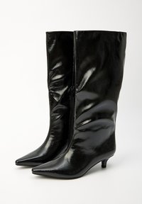 Bottes noires à bout pointu, en cuir brillant, avec une tige ajustée et froncée, et un petit talon. Elles disposent d'une fermeture à zip sur le côté.