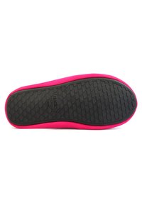 Suela de goma negra con un patrón texturizado, rodeada de una parte superior de tela brillante en color rosa. El diseño es elegante y minimalista.