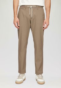 Beżowe, lekkie spodnie o prostym kroju z elastycznym paskiem w talii i kieszeniami z przodu. Połączone z białymi i beżowymi trampkami.