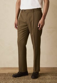 Brown checkered trousers with a tailored fit; features a button closure, side pockets, and a textured fabric.