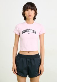 Light pink cropped t-shirt with "GODDESS" in bold black lettering, paired with black athletic shorts featuring a ribbed waistband and subtle accents.