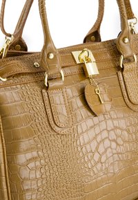 Sac à main en cuir d'alligator marron avec quincaillerie dorée, présentant un cadenas et un détail de porte-clés en forme de coeur. Design structuré et finition texturée.