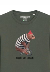 Groene katoenen t-shirt met een beer in gestreepte shirt en rode beanie, die fietst met de tekst "Tour de Franz" onder de afbeelding.