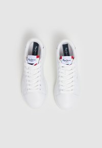 Sneakers bianchi con tomaia in pelle liscia. Presentano lacci piatti, perforazioni per la traspirabilità e una soletta con marchio arricchita da accenti rossi.