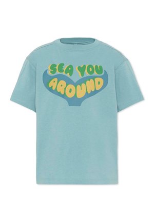 Camiseta de manga corta azul claro con un gráfico de cola de ballena azul y texto amarillo-verde "SEA YOU AROUND" en la parte delantera.