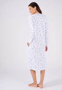 Noche largo de manga larga en tejido blanco con estampado floral azul. Presenta un corte recto y llega hasta la mitad de la pantorrilla.