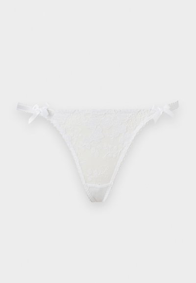 Λευκό δαντελωτό εσώρουχο σλιπ με κεντήματα λουλουδιών και μικρά φιόγκους και στις δύο πλευρές σε απλό φόντο.