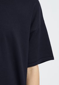 T-shirt bleu marine à manches courtes, texture côtelée, col rond et coupe décontractée avec des détails de couture nets et simples.