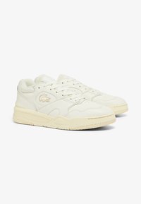 Zapatillas de piel blanca con acentos texturizados, diseño de cordones y una tapa del dedo clásico y redondeada. Detalle sutil del logo en el costado.