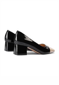 Scarpe con tacco a blocco in ecopelle nera lucida con punta beige, caratterizzate da una forma arrotondata e una texture liscia, progettate per il comfort e lo stile.