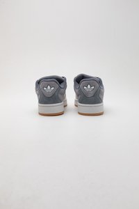Sneaker basse in suede grigio con suole in gomma bianca, caratterizzate da un collare imbottito, punta rotonda e una patch con logo sul tallone.