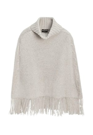 Poncho tricoté couleur crème avec un large col roulé côtelé et une longue frange le long du bord inférieur.