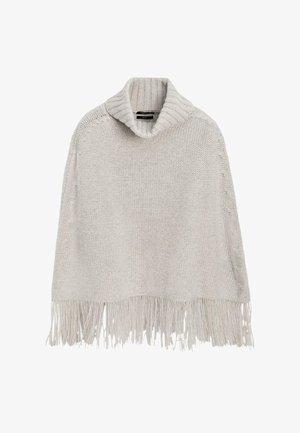 Cream-colored knitted poncho with a wide ribbed turtleneck and long fringe along the bottom edge.