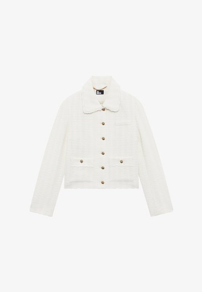 Veste courte blanche texturée avec des manches longues, un col pointu, six boutons dorés et trois poches avant avec des détails de boutons.