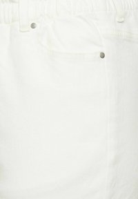 White denim pants with an elastic waistband. Features a front pocket and metal rivet detail, showcasing a smooth, textured surface.