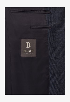 Interno di una giacca blu navy con tessuto liscio, due tasche e un'etichetta "BOGGI MILANO" grigia su uno sfondo marrone scuro.