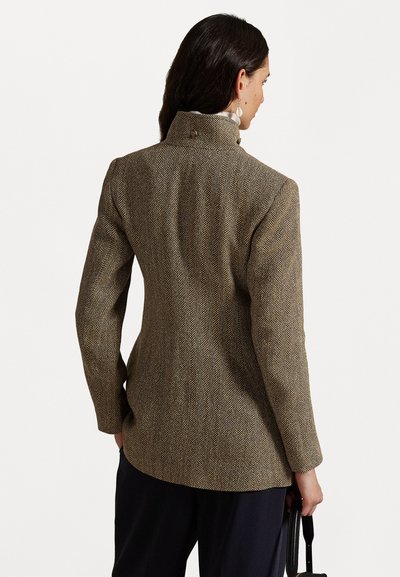 Hnědý blazer s rybí kostrou a vysokým límcem, se dvěma knoflíky na zádech a přiléhavým designem. Materiál vypadá texturovaně a strukturovaně.
