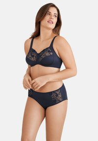 Navy komplet bielizny z biustonoszem z przezroczystymi koronkowymi detalami i pasującymi wysokimi figami. Oba elementy zdobią kwiatowe wzory na koronce.