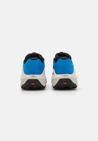 Baskets de sport avec une tige bleue et des accents noirs, un collier rembourré et une semelle intermédiaire texturée blanche. Détail rouge sur la semelle extérieure.