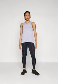 Lys lilla singlet med tynne stropper, kombinert med svarte leggings. Singlet har minimalistiske detaljer og en avslappet passform.