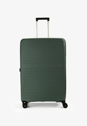 Valise rigide verte avec des lignes diagonales et horizontales texturées, poignée télescopique et quatre roues pour une mobilité facile.
