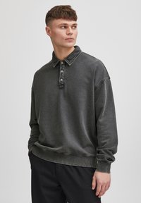 Grau pullover mit Kragen und Knopfleiste mit drei Knöpfen. Verfügt über lange Ärmel, eine lockere Passform und sichtbare Nähte.