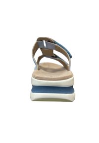 Lichtblauwe sandaal met een gevoerde zool, voorzien van een zachte, textuurachtige bovenkant en een verstelbare enkelband. Stevige witte basis met blauwe accenten.