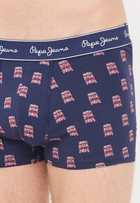 Navyfarbene Boxershorts aus weichem Stoff mit einem wiederholten Muster aus roten Doppeldeckerbussen. Elastischer Bund mit "Pepe Jeans"-Logo.