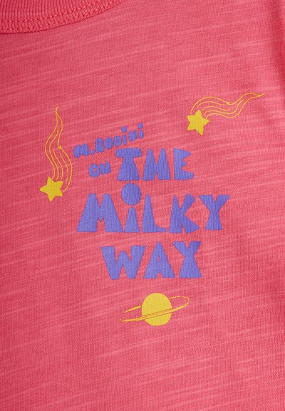 Μωβ κείμενο που γράφει «Μ. Ροδίνι στον Γαλαξία» με κίτρινους πεφταστέρια και έναν κίτρινο πλανήτη με δαχτυλίδια σε ροζ φόντο υφάσματος.