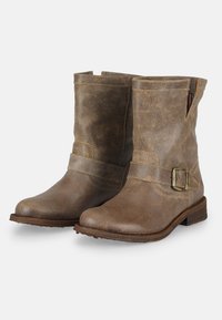 Botas de tobillo de cuero marrón con un acabado texturizado, detalle de correa con una hebilla de metal y un tacón de madera bajo.