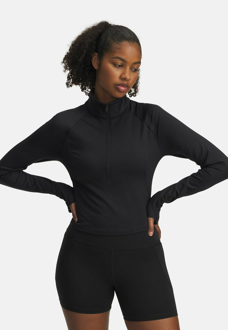 Black long-sleeve athletic top with a half-zip collar, paired with black shorts. Features stretchy, smooth fabric with fitted design.