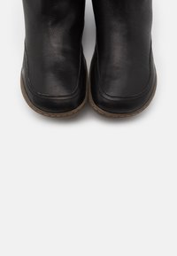 Schwarze Leder-Stiefeletten mit glatter Oberfläche, runder Zehenpartie, dezenter Naht und einer hellbraunen Gummisohle.