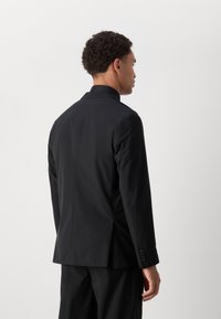 Black suit jacket with a tailored fit, featuring a notched collar, smooth texture, and button accents on the cuffs. Back view displayed.