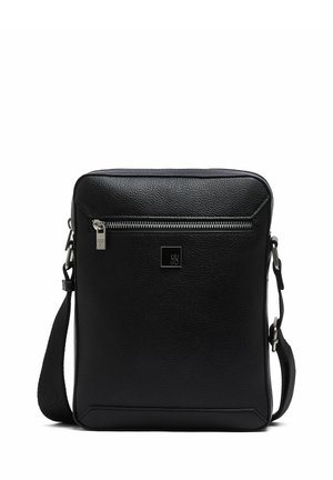 Sac bandoulière en cuir noir avec poche avant zippée, sangle d'épaule réglable et petite plaque logo carrée à l'avant.