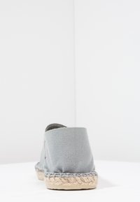 Gray canvas espadrille with a braided jute sole, rounded back, and minimalistic design. Textured, soft fabric with subtle color variation.