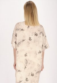 Lätt, beige kimono med svart blommönster. Har korta ärmar och en avslappnad passform. Mjuk, slät textur med en flödande design.