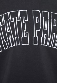 Černý oděv s nápisem "STÁTNÍ PARK" velkými bílými blokovými písmeny, s hladkou texturou a neformálním designem.