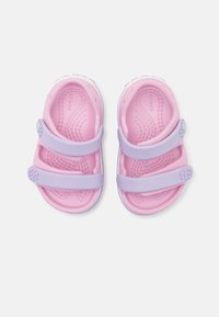 Růžové a levandulové sandály se dvěma nastavitelnými popruhy, vyrobené z lehkého materiálu, s texturovanou stélkou a kruhovými akcenty.