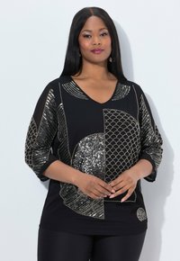 Zwarte top met een V-hals, voorzien van zilveren geometrische paillettenpatronen en metallic accenten, driekwartmouwen en een relaxte pasvorm.