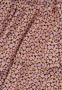 Een gelaagde rok met een oranje en lavendelkleurig luipaardprintpatroon op een donkere achtergrond, met een rekbare tailleband voor extra comfort.