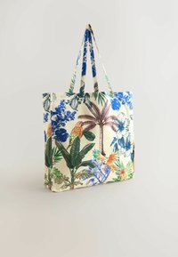 Tote bag lavet af stof med en cremet baggrund, der har livlige blå blomster- og grønne bladmønstre samt farverige papegøjer, med lange håndtag.