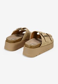 Sandalias de plataforma beige con correas de textura floral, hebillas ajustables y una plantilla acolchada color marrón. Presenta una suela gruesa de color claro.