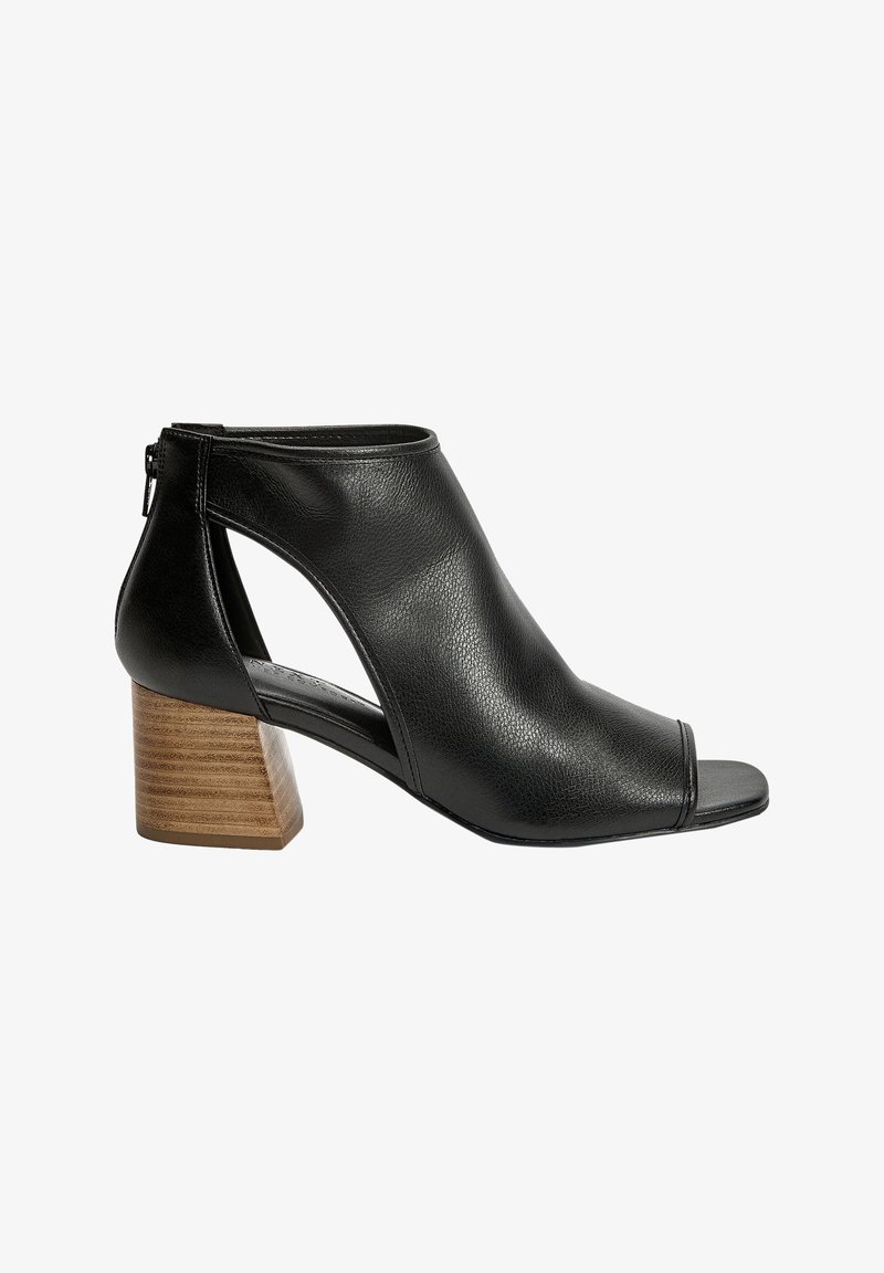 Botte cheville en cuir noir à bout ouvert avec côtés découpés et talon bloc en bois. Texture lisse et design minimaliste. Fermeture éclair à l'arrière.