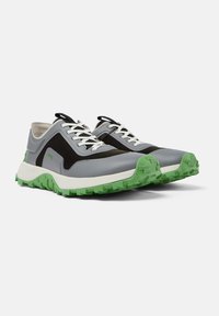 Sneakers con tomaia grigia, pannello in rete nera e suola in gomma verde. Presentano lacci bianchi e una finitura testurizzata.
