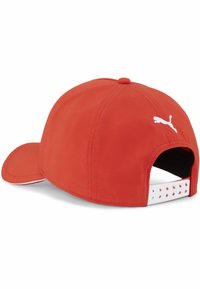 Czerwona czapka z zaokrąglonym daszkiem, wykonana z gładkiego materiału. Zawiera biały logo oraz regulowany pasek z wycięciami z tyłu.