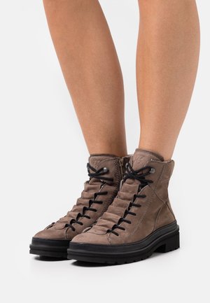Stivaletti mid-top in pelle marrone con superficie testurizzata, dotati di lacci neri, una cerniera laterale e una suola chunky nera.