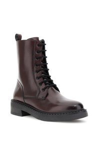 Stivale alla caviglia in pelle marrone scuro con lacci, suola nera spessa e linguetta sul retro, mostrato da un leggero angolo su sfondo bianco.