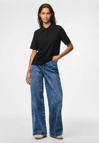 Black short-sleeve polo shirt with a collar and three-button placket paired with high-waisted, wide-leg blue denim jeans.