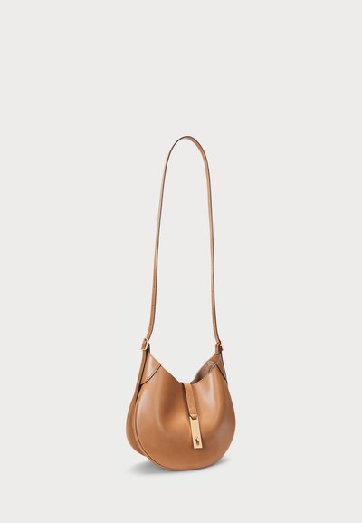 Τσάντα ώμου από ταμπά δέρμα με καμπυλωτό σχήμα, ρυθμιζόμενο λουράκι και αξεσουάρ χρυσού τόνου στο μπροστινό μέρος. Λείου υφής και μινιμαλιστικού σχεδιασμού.