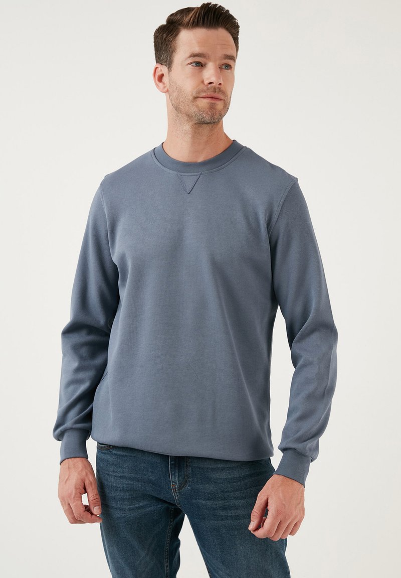 Felpa in cotone blu con collo a giro e maniche lunghe, caratterizzata da una finitura testurizzata e un dettaglio di cucitura triangolare sul colletto.